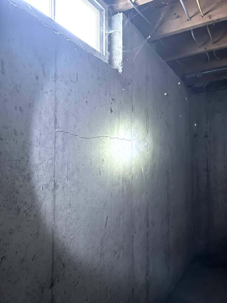 Mur de fondation en béton éclairé à la lampe de poche, fissure visible