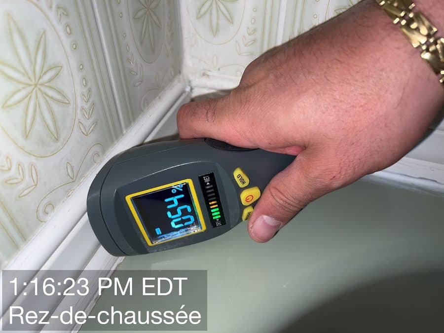 A moisture meter being used to take a reading on a wall